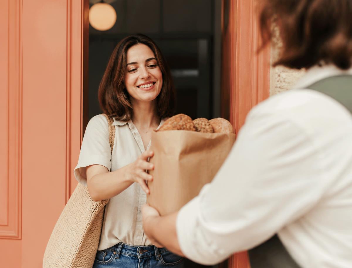 A customer collecting a paper bag of fresh bread at pickup